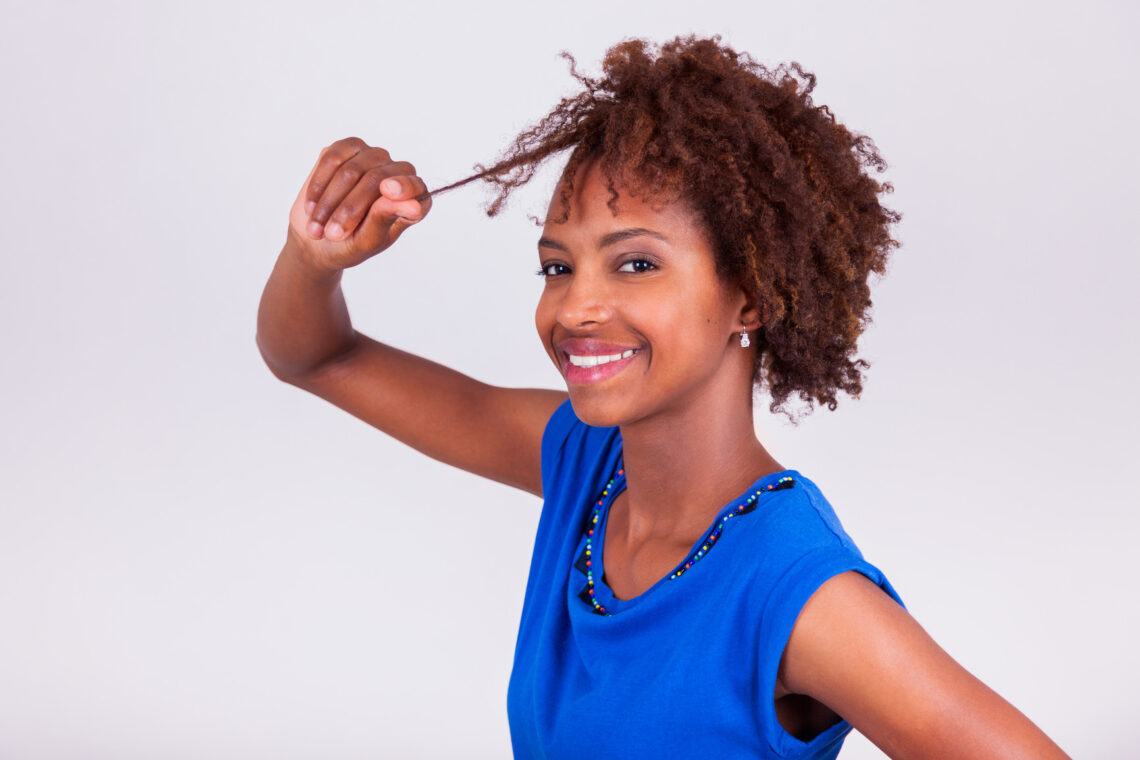 Young African American woman holding her frizzy afro hair - Blac